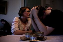 A woman comforting a crying man with his face in his hands.