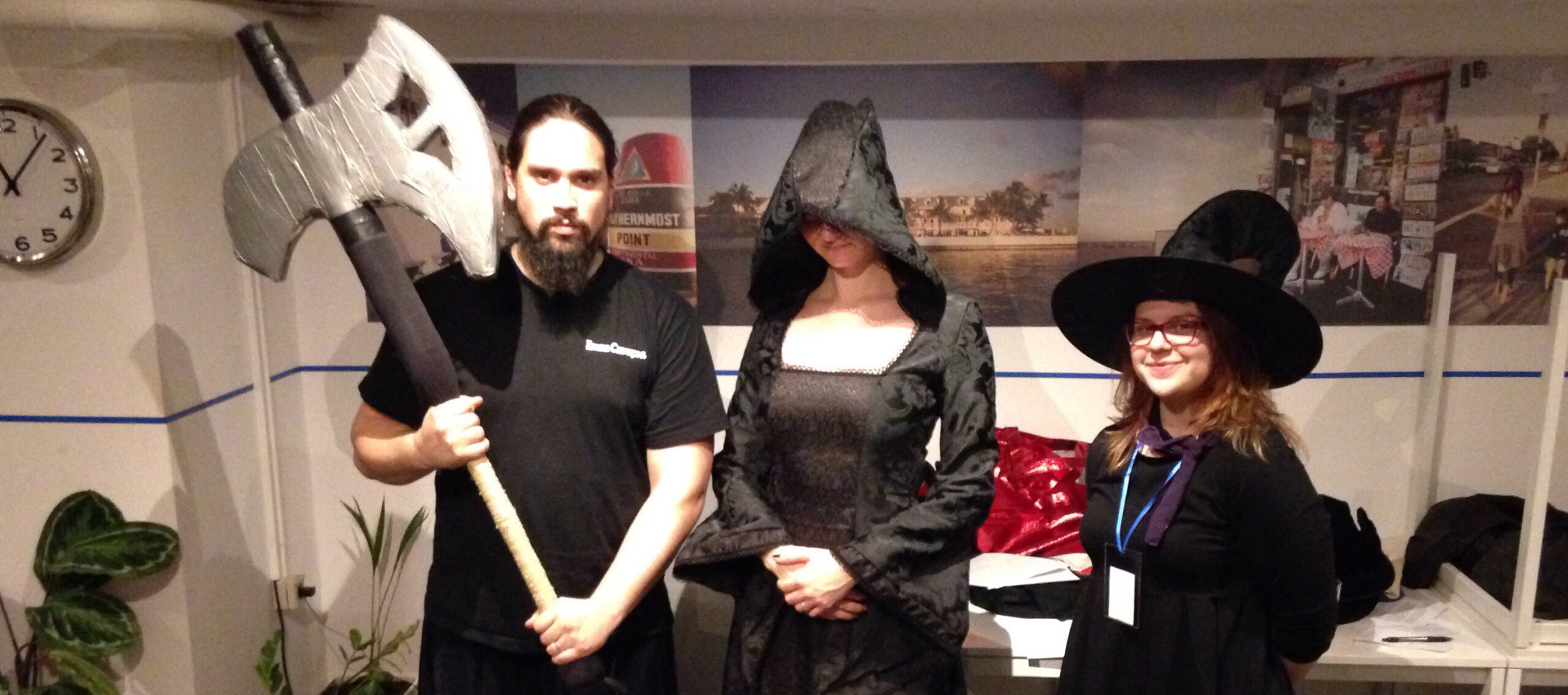 People holding a boffer weapon and wearing witch costumes