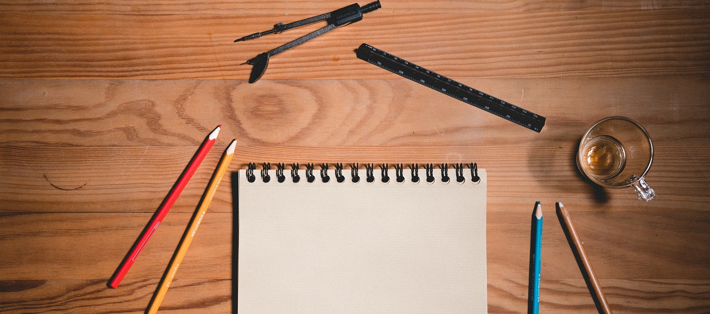 photo of a blank pad of paper with pens, pencils, a coffee cup, and a protractor