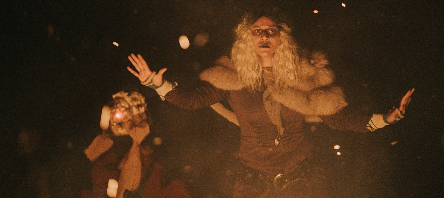 Photo of Aina Skjønsfjell with arms wide over a fire