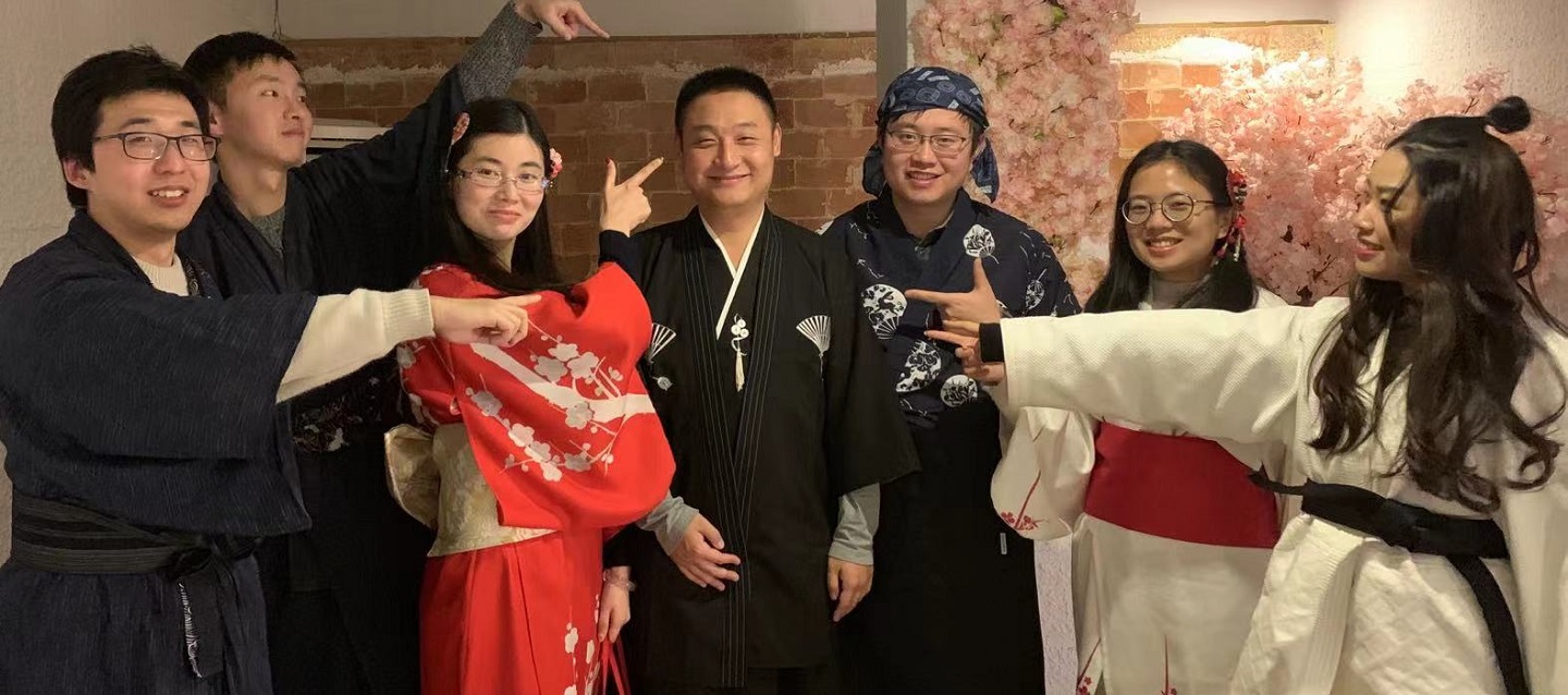 people in Chinese costumes pointing at a person in the middle of the group while smiling