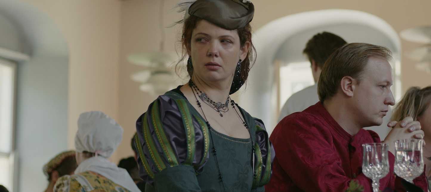 Photo of woman people in period costumes sitting at a dinner table